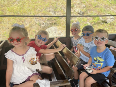 Children on train wearing red white and blue star sunglasses at Tweetsie Railroad